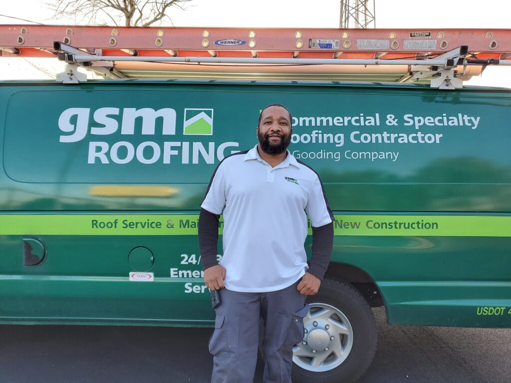 Joel Mondesir standing in front of a GSM Roofing van