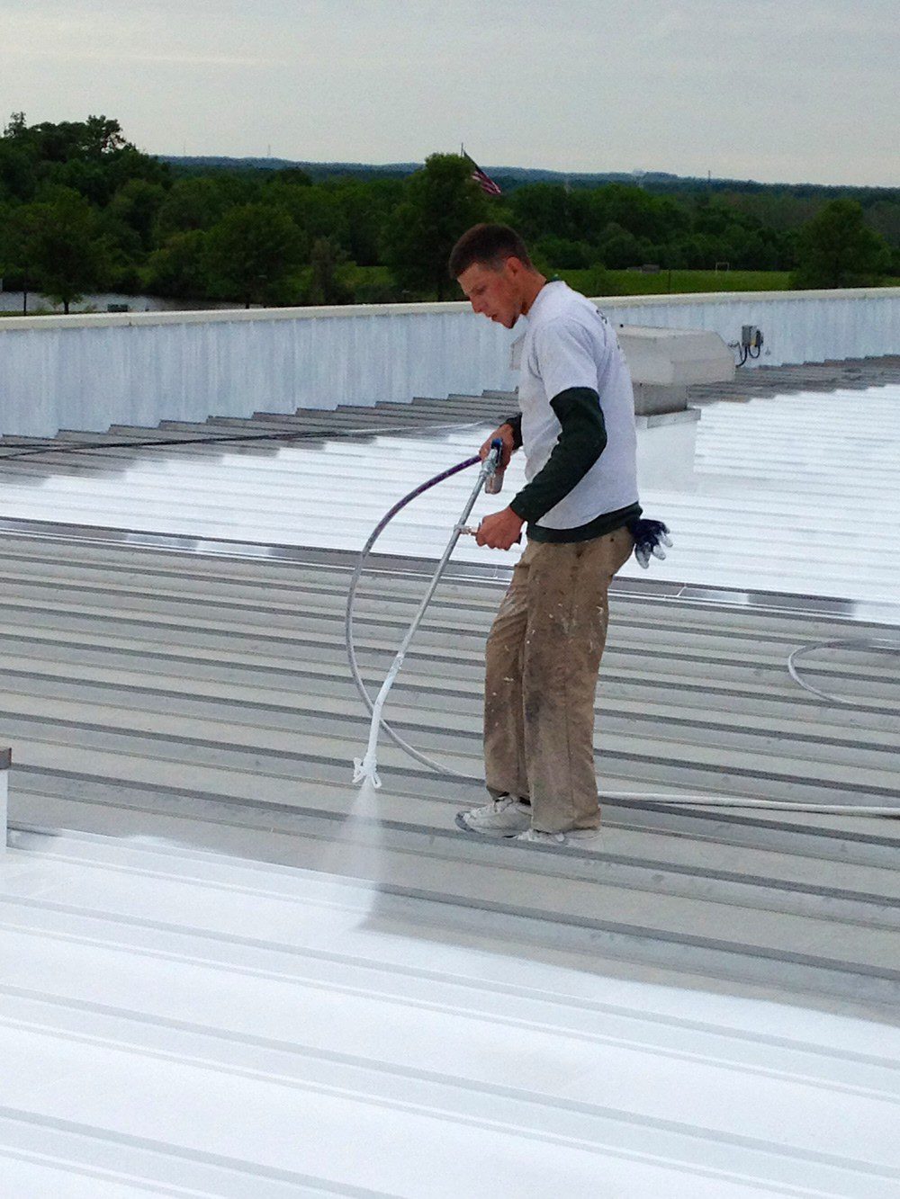 Roofer applying white roof coating for commercial rooftop