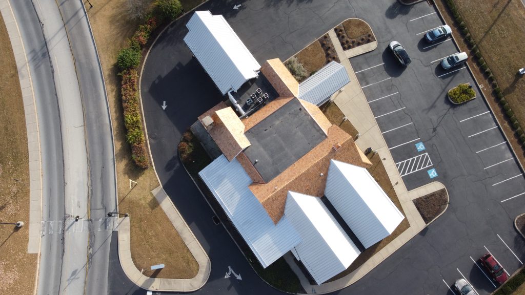 Top-down aerial view showing completed cedar shake, EPDM, and metal roofing sections on S&T Bank.