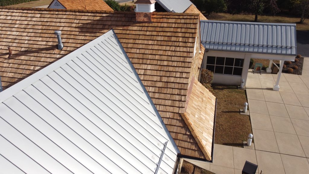 Close-up of restored cedar shake roof integrated with existing metal roofing sections on commercial building.