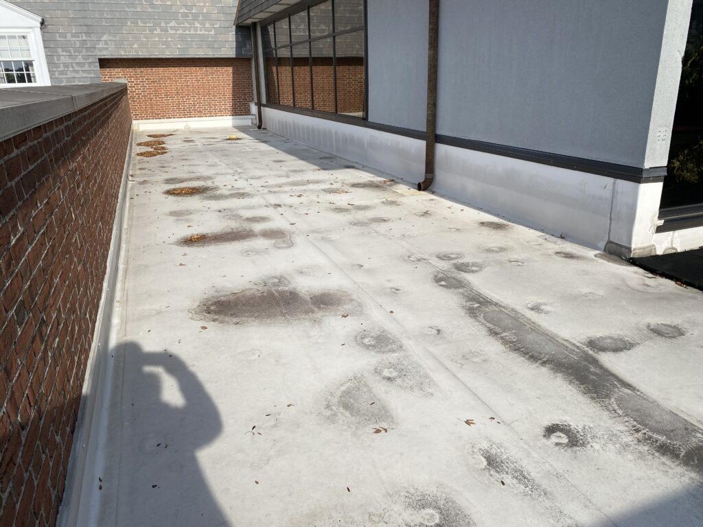 Rooftop with deteriorated black rubber mats and visible moss growth on TPO membrane before GSM Roofing began the roof deck upgrade.