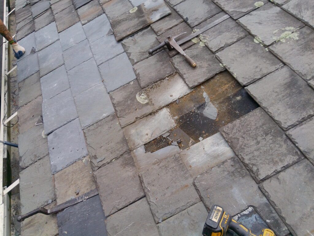 GSM Roofing Master Pro Certified Installer performing Vermont Gray slate repair in progress at St. Matthew Roman Catholic Church Tyrone PA showing exposed underlayment failed tiles removed and specialty slate tools 2026